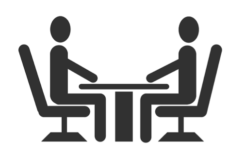 Siluetas humanas sentadas y en medio una mesa.