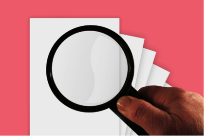 Mano sosteniendo lupa sobre documentos en blanco.