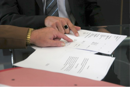 Dos manos sobre páginas de un contrato señalando líneas con el índice.